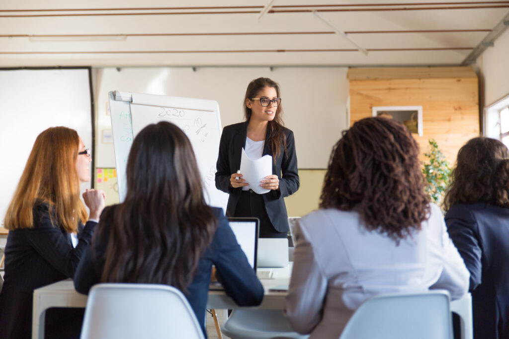 businesswomen looking at speaker with papers
